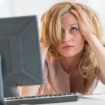 Frustrated Businesswoman With Hands In Hair At Office Desk