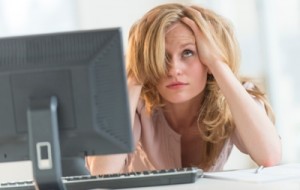 Frustrated Businesswoman With Hands In Hair At Office Desk