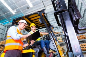 Asian lift truck driver and foreman in storage